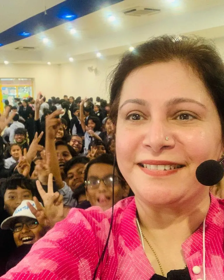 Shefali Chopra with a full school hall of cheering students behind her
