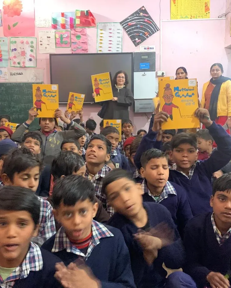 Children in a classroom holding up storybooks